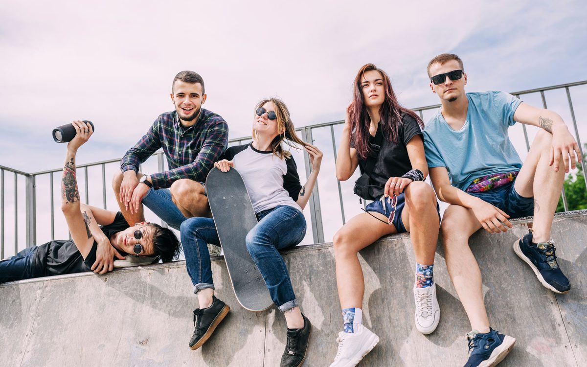 Group of friends sitting on a concrete ledge taking photos on a sunny day