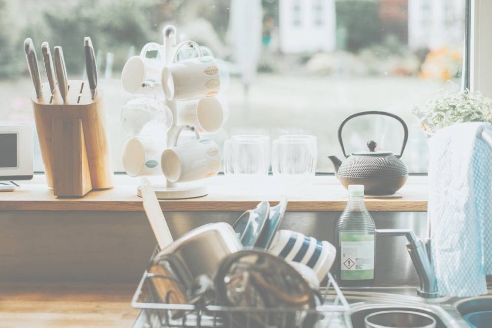 Bright kitchen counter with dish rack and kettle